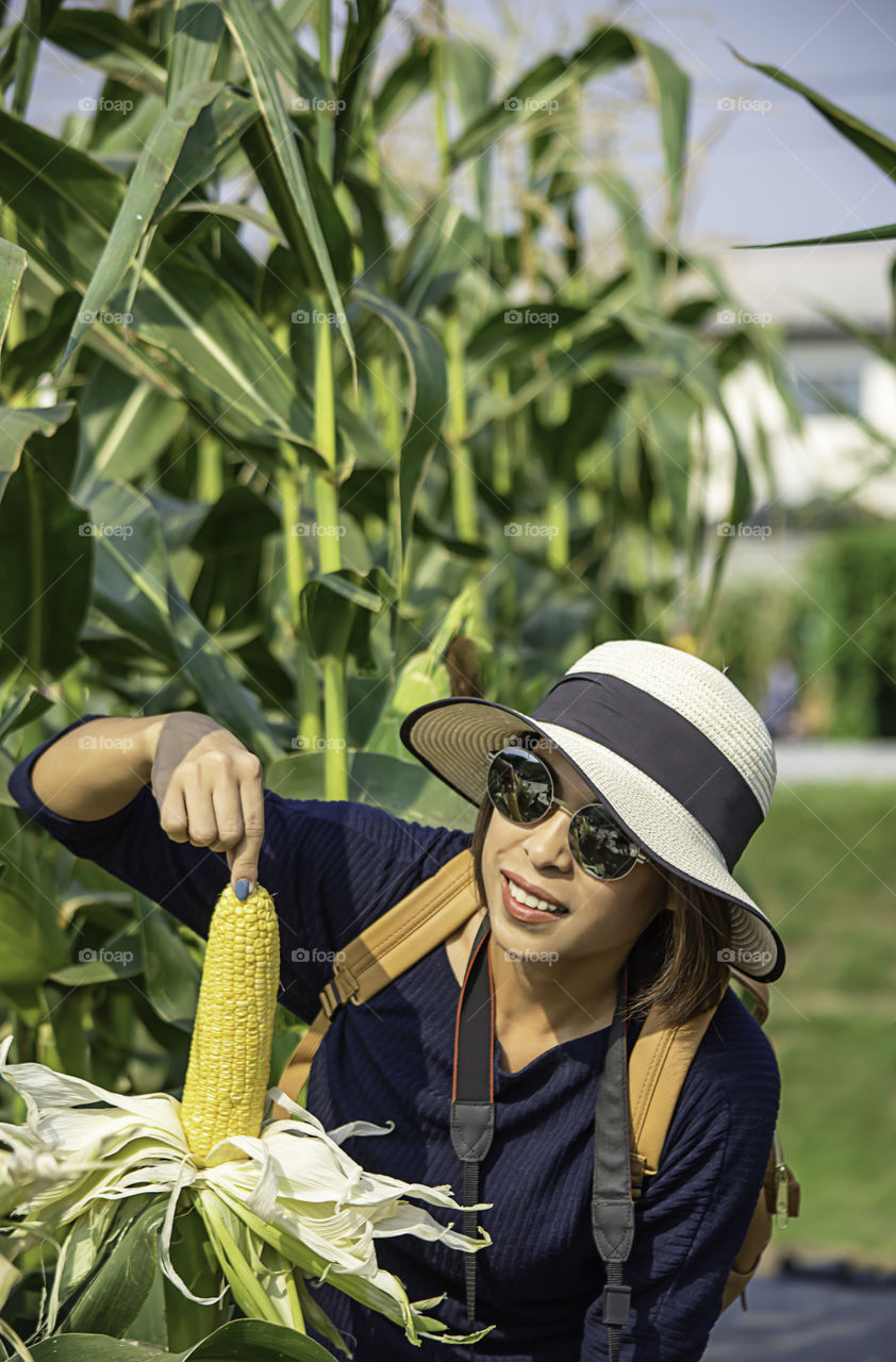 A woman holding the corn at the show in the farm.