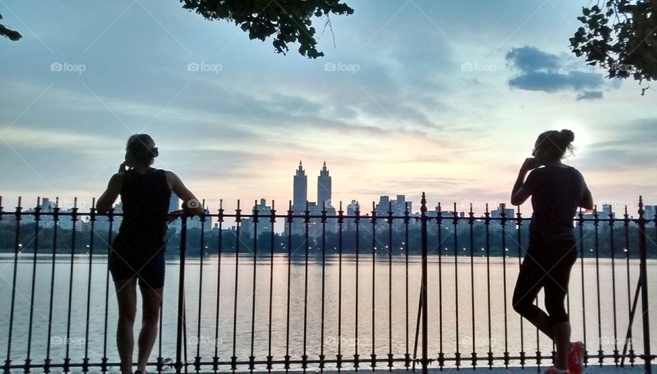 Two people leaning against railing at sunset