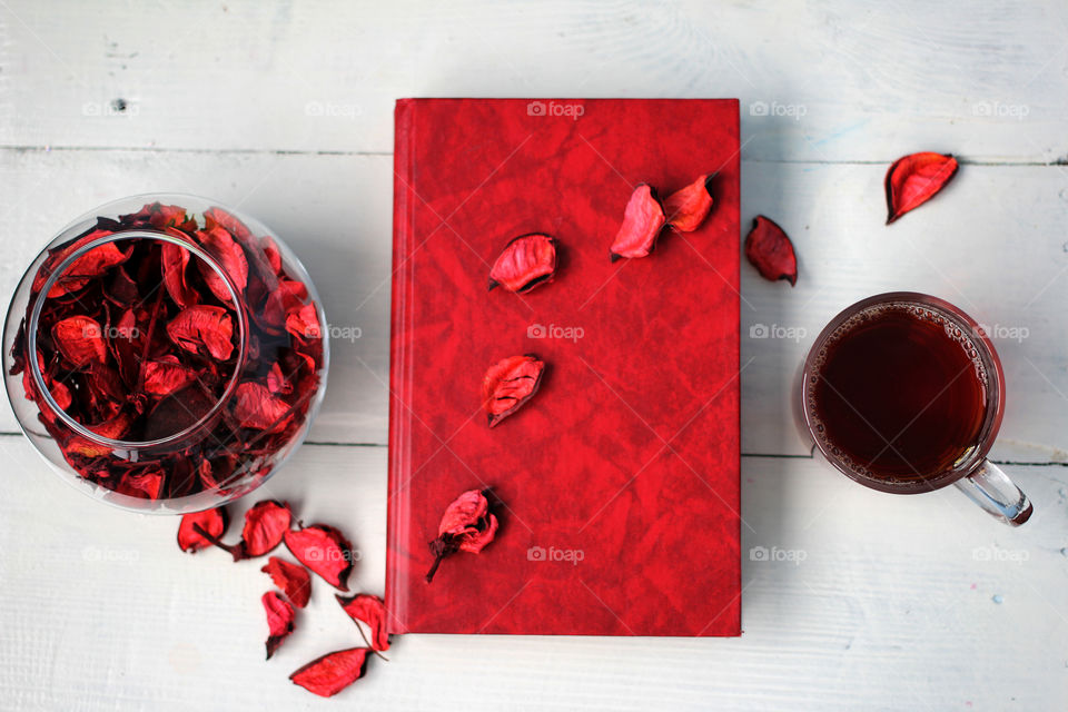 Cup of tea with a book and petals white table