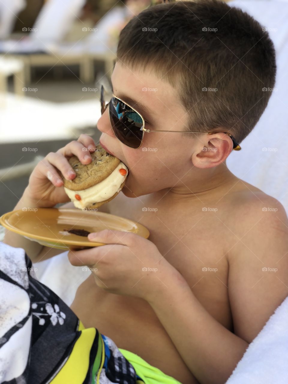 A young boy enjoys an ice cream sandwich poolside while on vacation in Las Vegas.