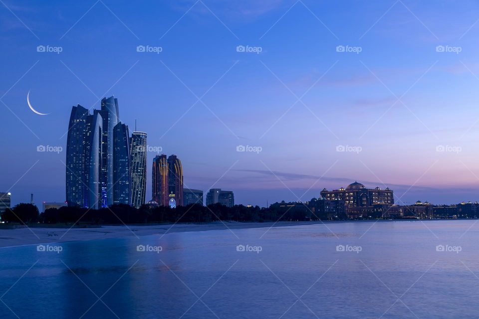 Dawn in Abu Dhabi with crescent moon in the blue sky