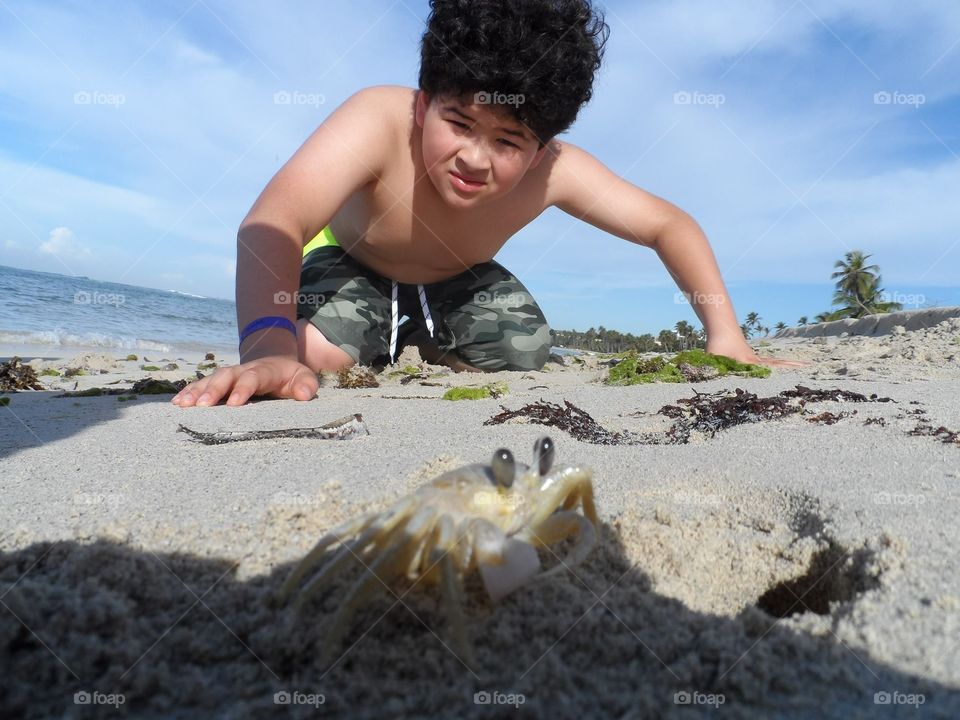 The kid and the crab. Kid at the beach looking at a crab