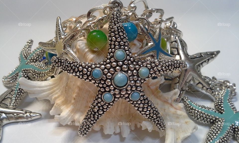 blue green silver starfish necklace on seashell