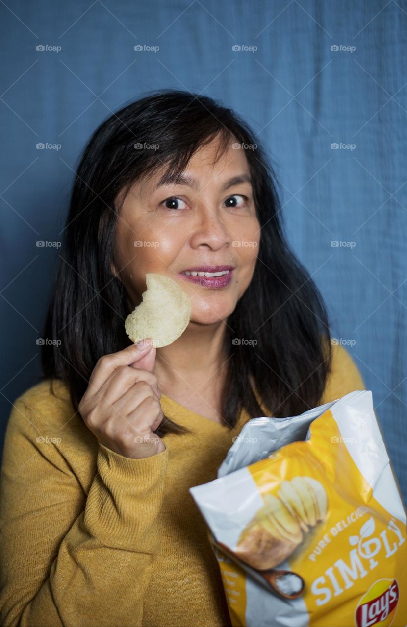 Portrait of a woman eating potato chips 