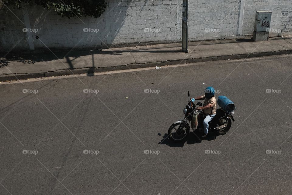 Motorcyclist riding on the road carrying a gas balloon in the daytime