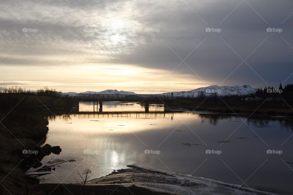 Sunset over river and bridge in Thingvellir National park in Iceland with clouds on the sky.