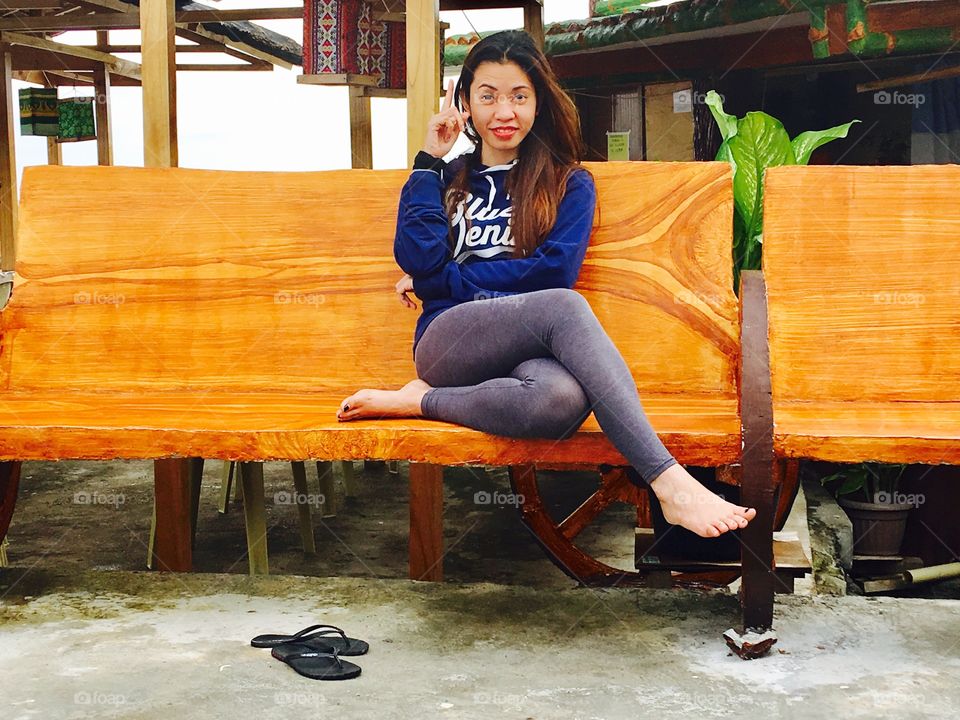 A girl sitting on the bench happily.