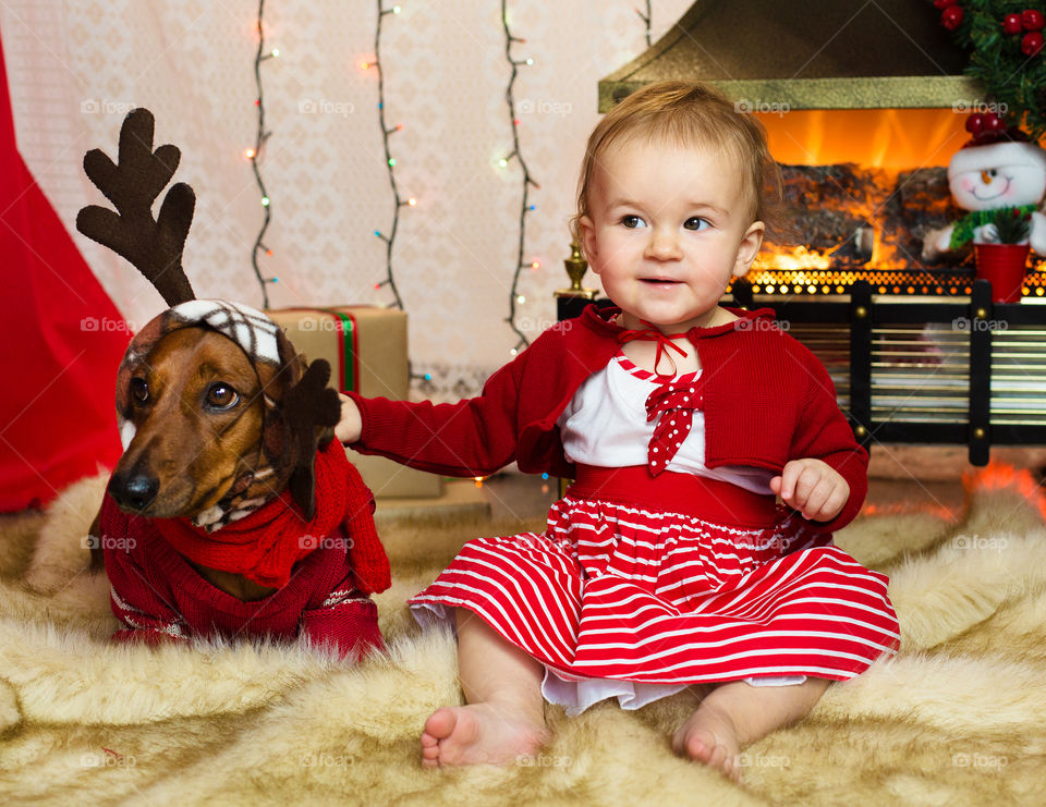 Cute baby with lovely dog near the fir-tree 