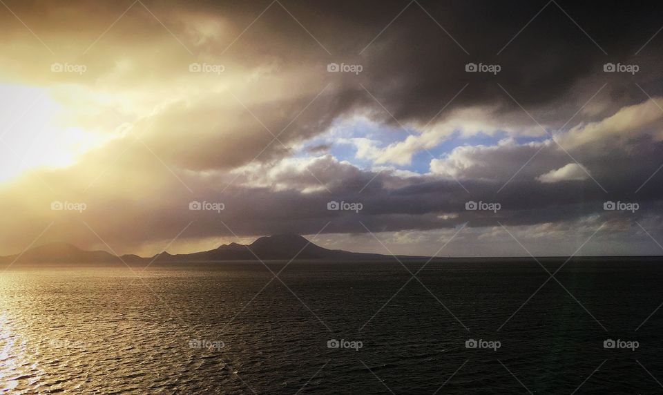 Morning sunshine rises over the islands.  A peek of blue shows through the puffy, white clouds. 