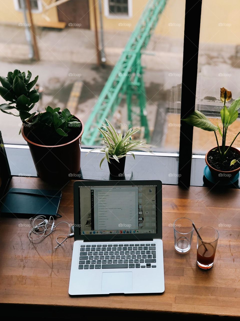 An open computer stands on a wooden table by a window in a modern cafe, nobody 