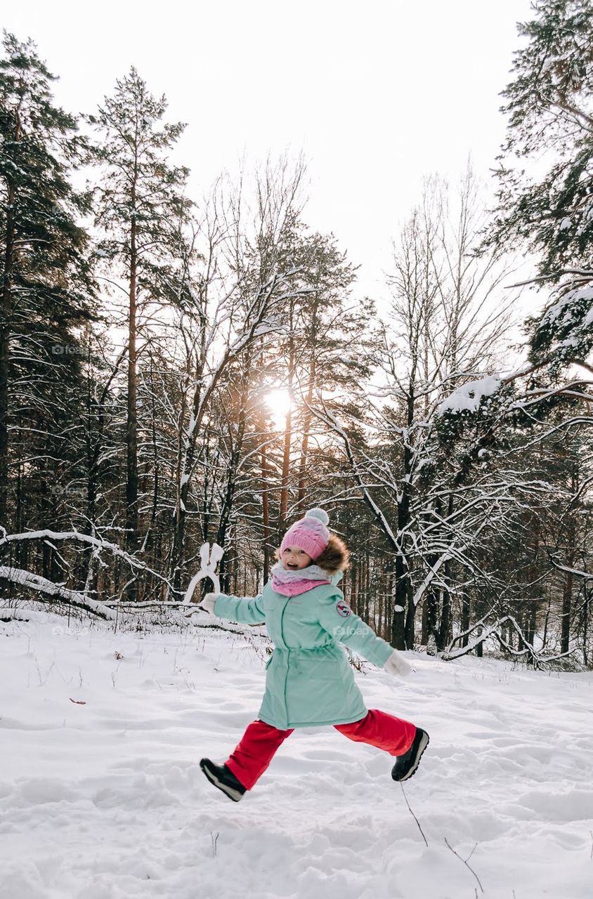 Girl is walking in the winter forest.