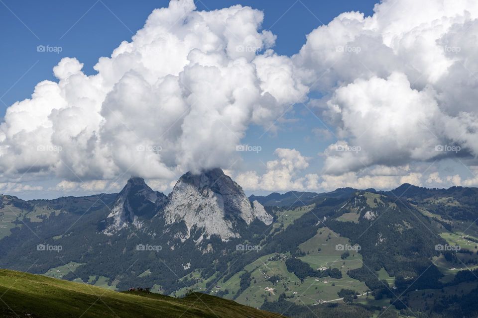 Beautiful white large clouds froze over the mountain, like a volcanic eruption in Switzerland with a beautiful mountain landscape, close-up side view. Cloud concept, beautiful scenery wallpaper, nature and environment.