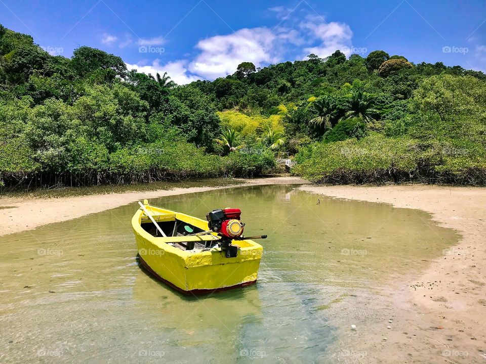 little yellow boat on the shore of a desert island