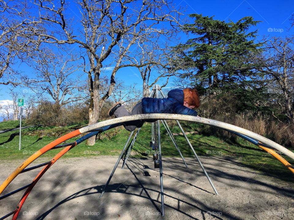 Toddler playing on the monkey bars. 