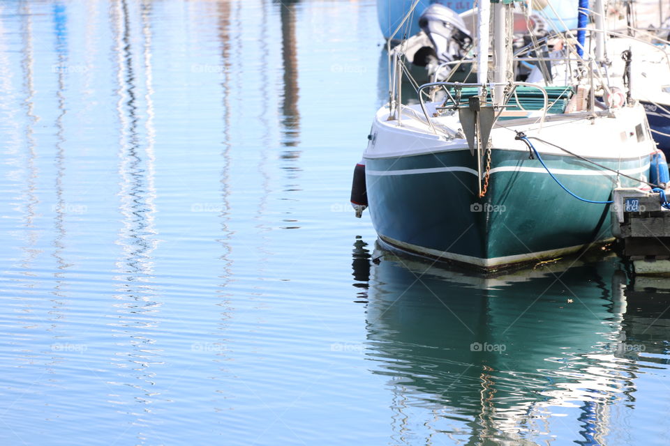 Green and white coloured boat siting in the harbour 