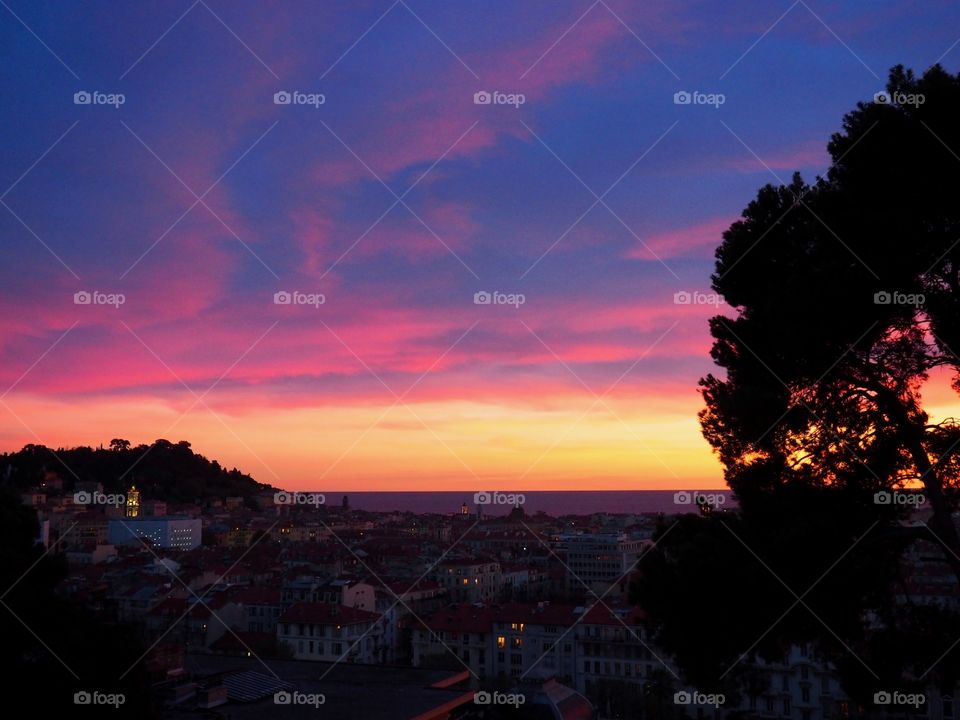 View of colorful sky at sunset overlooking the old town and sea in Nice, France.