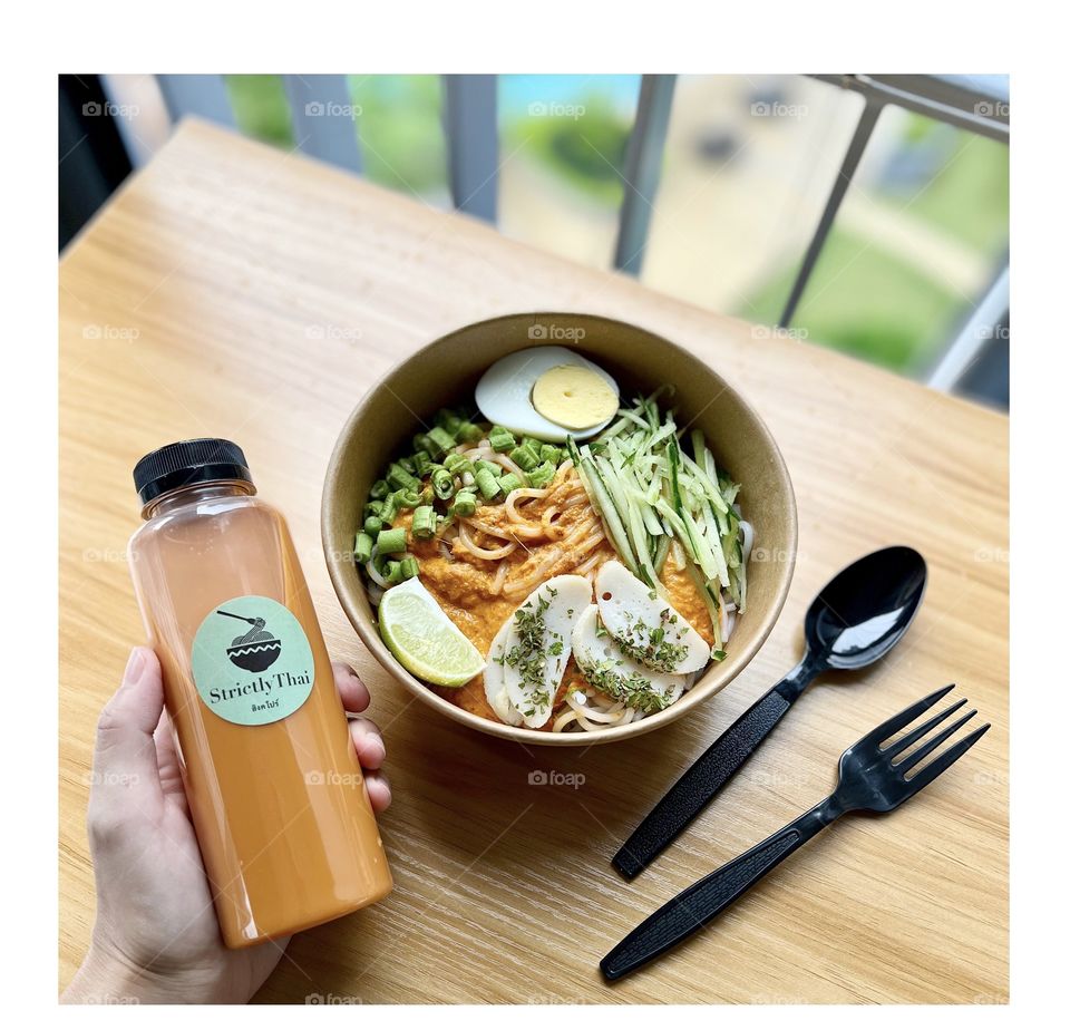 Khanom jeen namya thailand dry laksa fish with fish curry, boiled egg, fresh greens and fishcake slices and Thai milk tea 