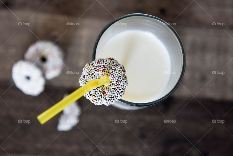 Top view of a glass of milk and chocolate sprinkle cookies on a table