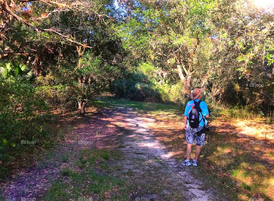 A man walking through the sunlit forest.