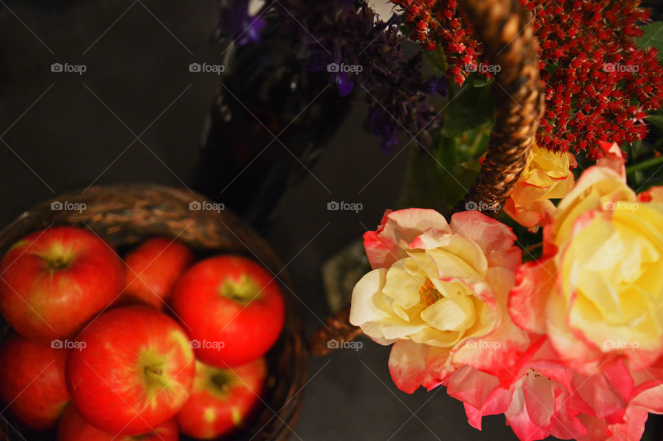 Bouquet of fall flowers next to basket of apples high angle view conceptual healthy eating fall harvest background with soft focus and room for copy