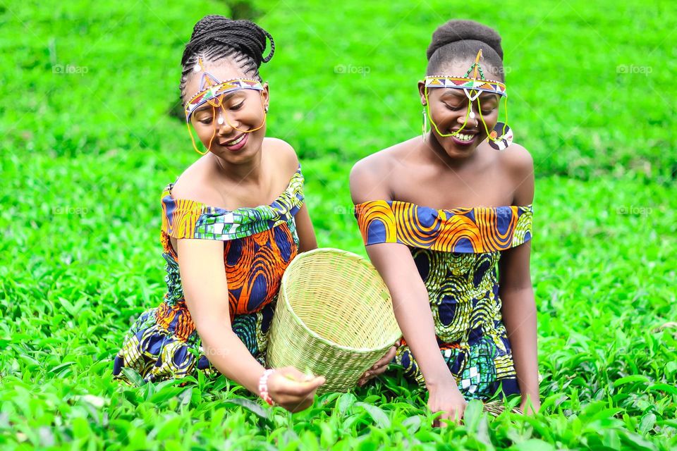 Two beautiful Black African women green tea farm wearing African traditional clothes, with a beautiful smile on her face.