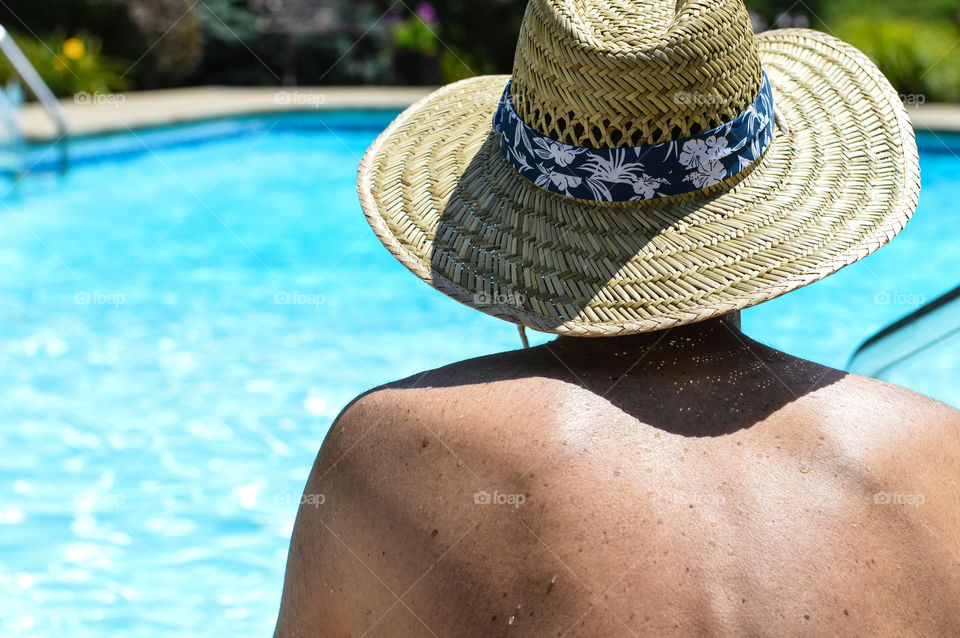 Man wearing a sun hat and overlooking the pool