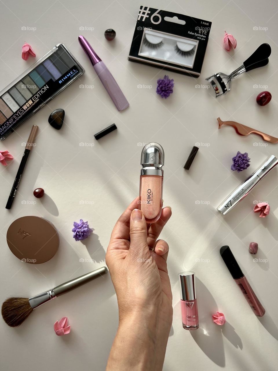 Decorating cosmetic. Hand holding the pink lipgloss. Lot’s of beauty brands.