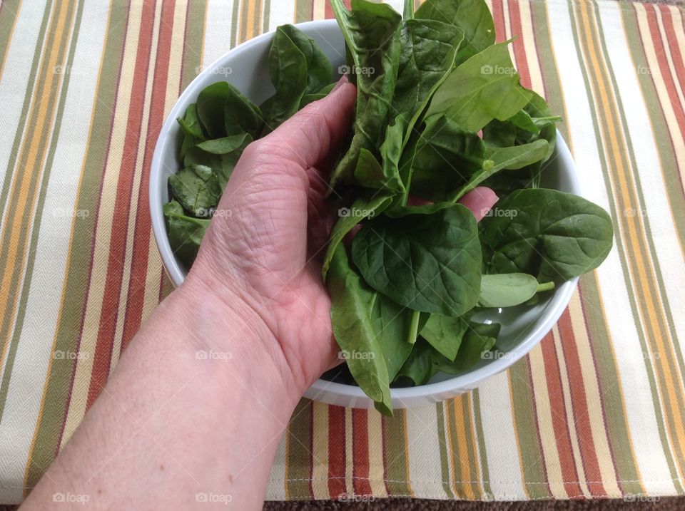 Holding a handful of spinach.