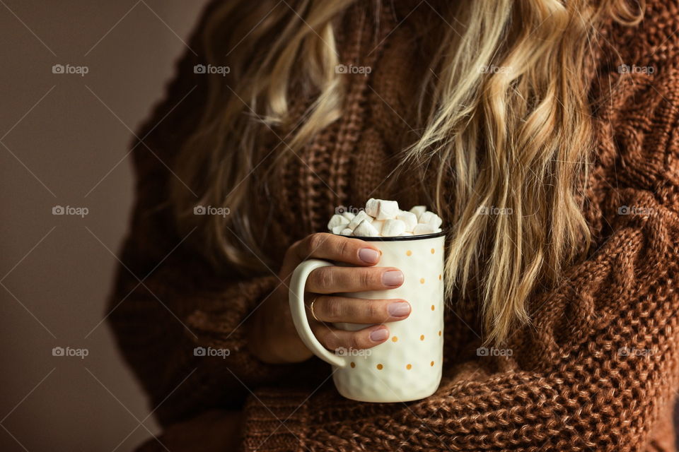 Female hand holding cup of coffee with marshmallow 