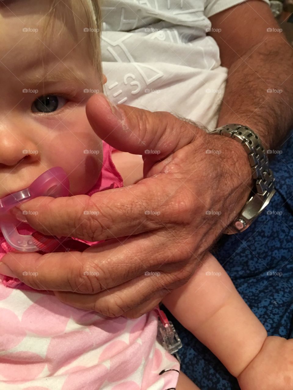 Hold the pacifier. Grandpa helping granddaughter with her pacifier