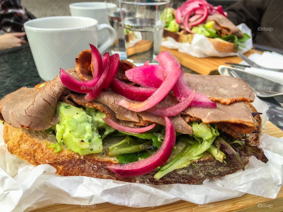 Lunch outdoors with delicious sandwich with roast beef, vegetables and pickled onion. 