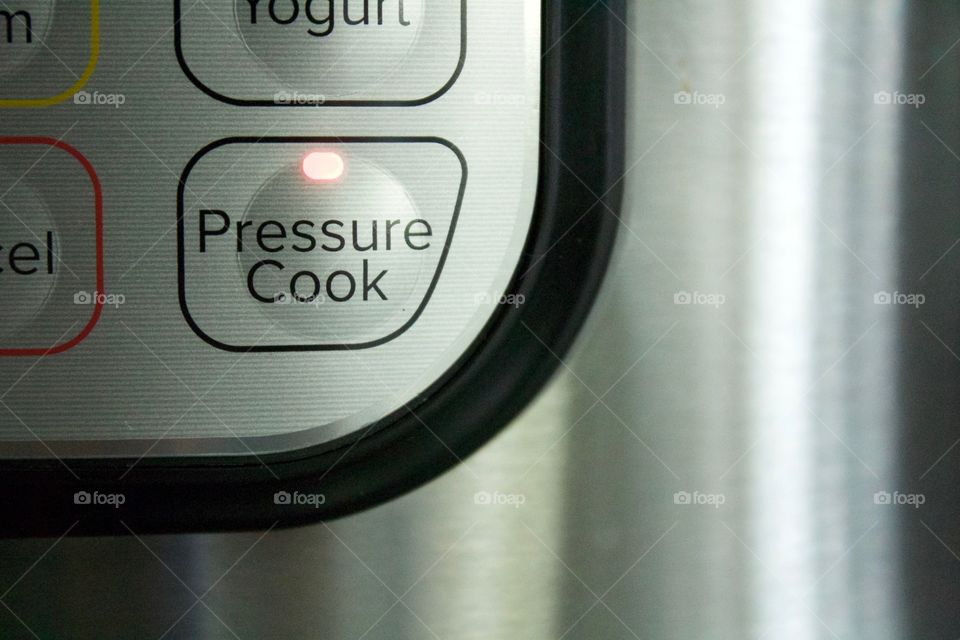 LED lIght on an electric pressure cooker control panel button showing that the pressure cooking option has been selected