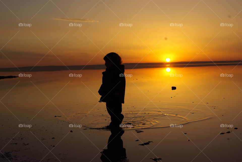 Silhouette of child walking on lake
