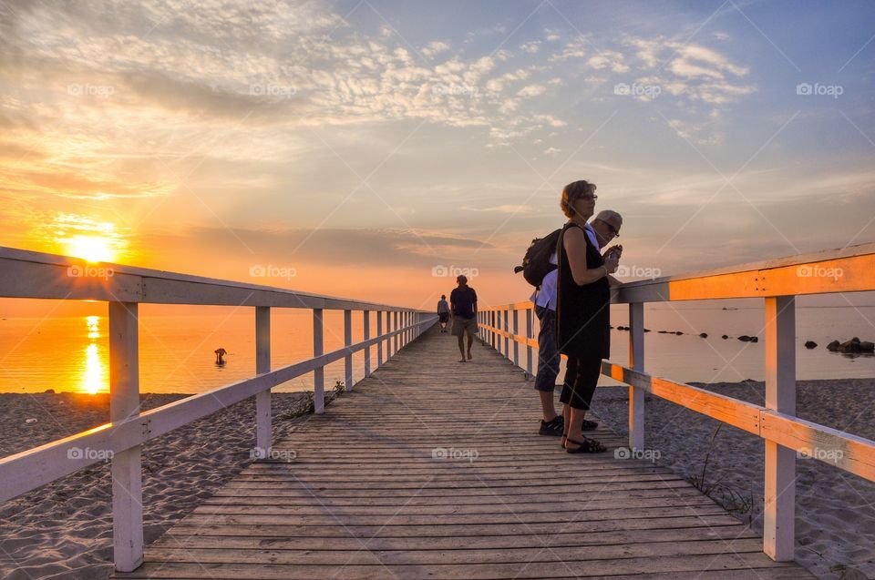 People standing on wooden pier during sunset