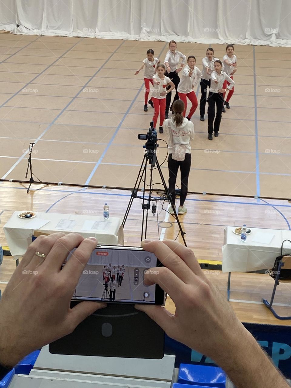 The proud parent filming their girls dance competition from the top of the bleachers.