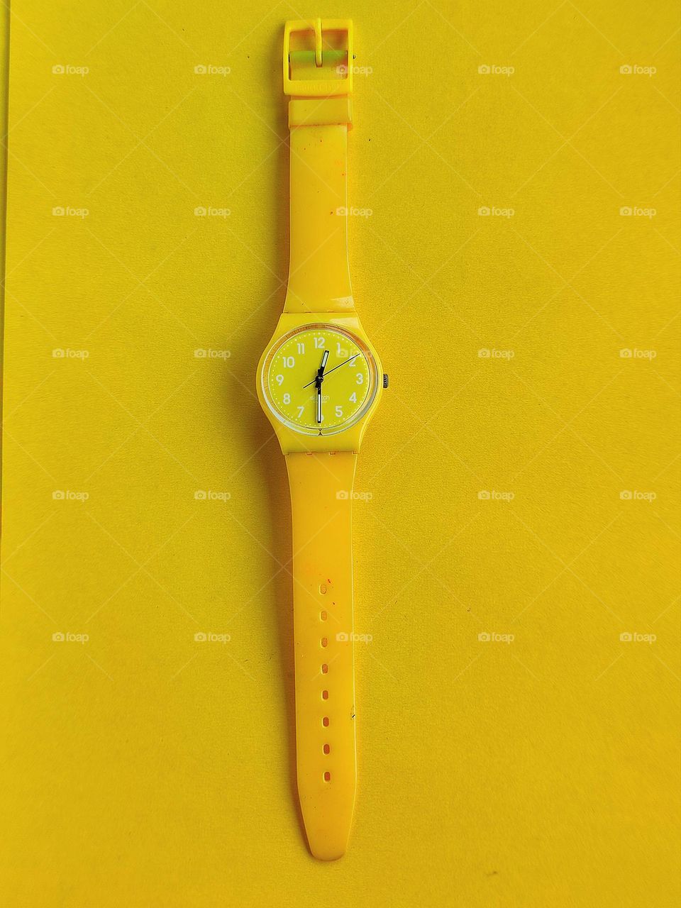 Yellow.  On a yellow background lies a yellow hand watch