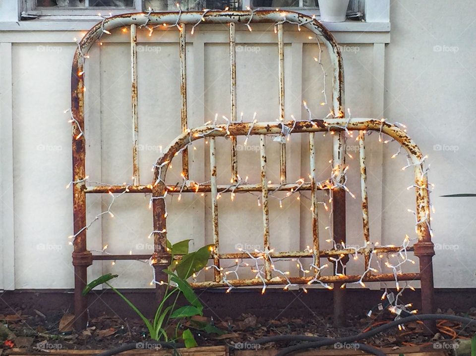 Rusted metal bed headboard and footboard decorated with white twinkle lights