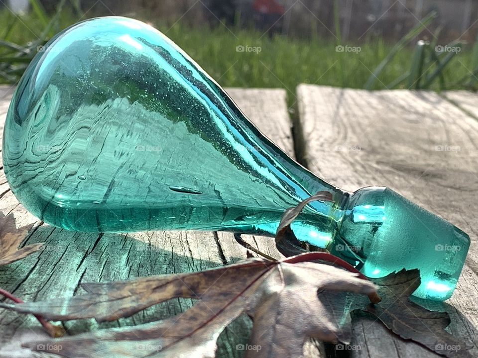 A bauble in the mid-morning sun. Glass, with the Autumn leaves, reflecting in the sun. 