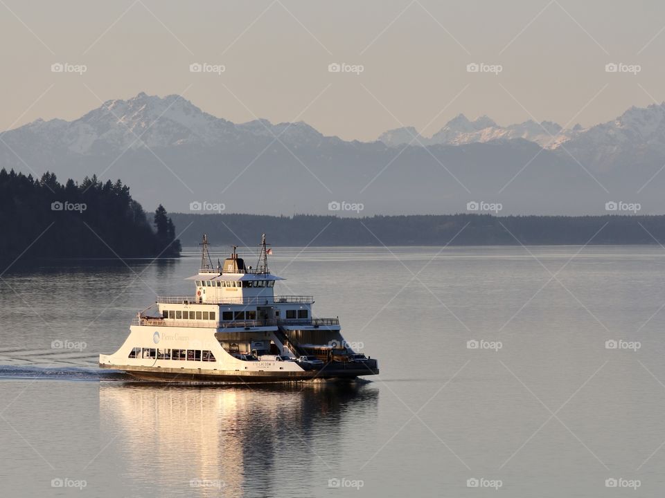 The Puget Sound Ferry comes to dock in Steilacoom, Washington on a clear day with the Olympic Mountains in view