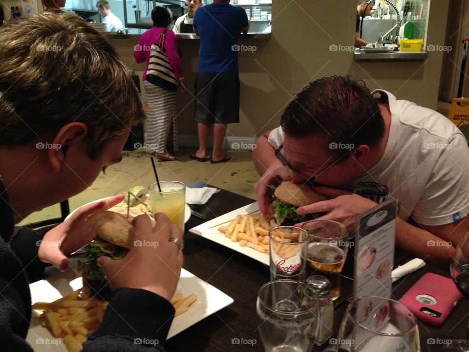 Hungry guys eating enormous burgers. Hungry guys eating enormous burgers