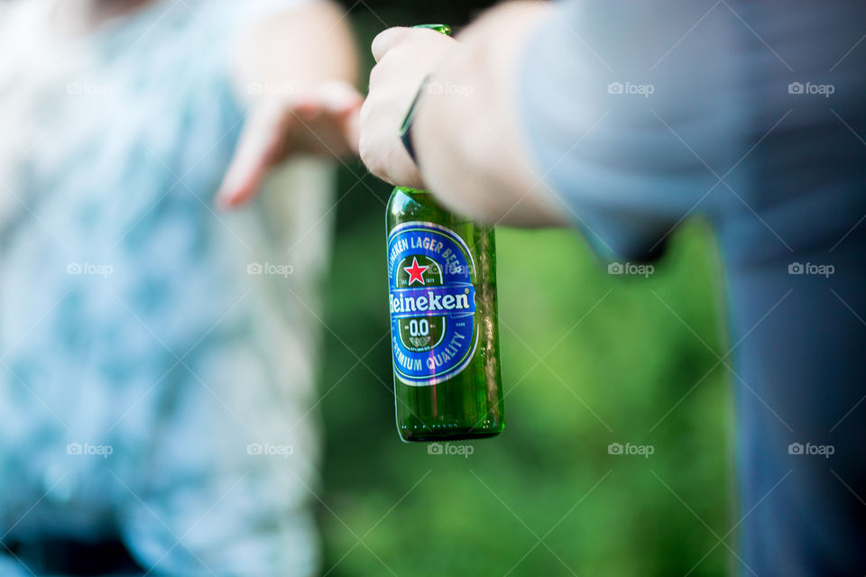 Nonalcoholic Heineken bottle in man hand on picnic 