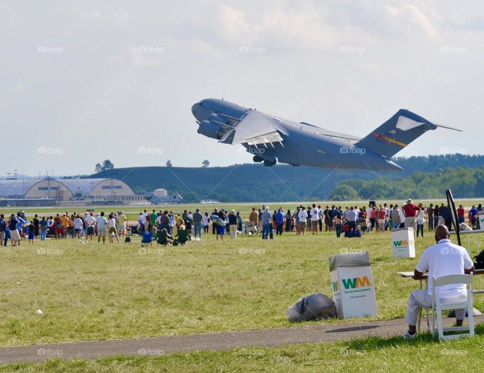 Huge USA military jet taking off over a group of people