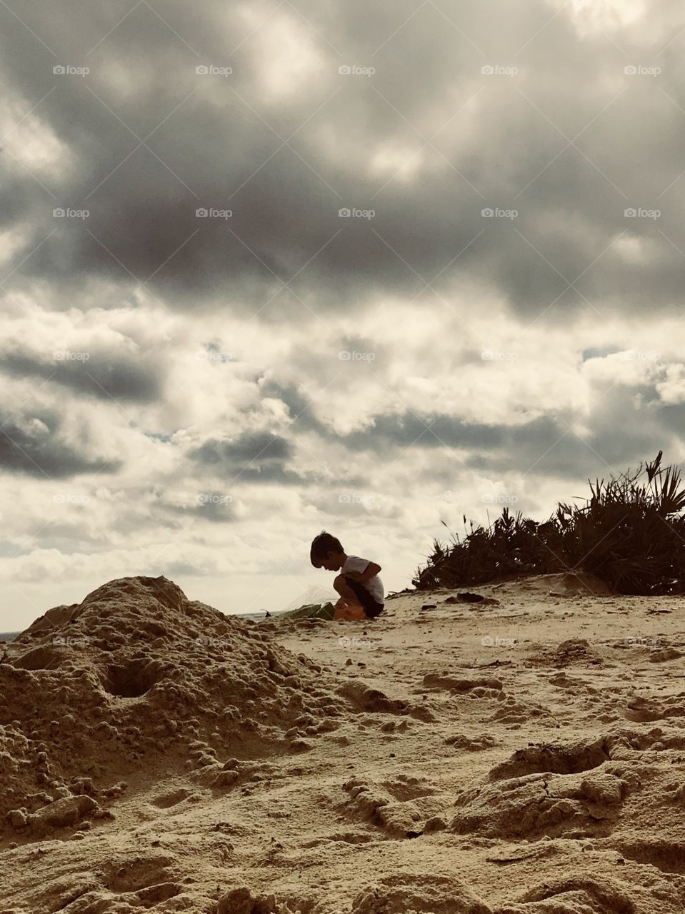 Boy playing in the sand next to the ocean waves