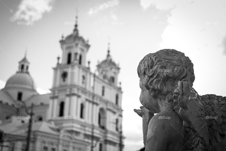 A statue of an angel blowing a kiss to a church in the amazing town of Grodno