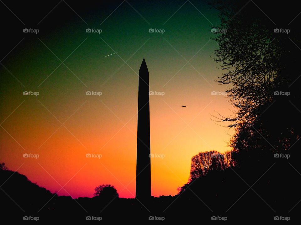 Shooting Star in D.C.. Taking a photo if the Washington Monument during the sunset . In the background an airplane is climbing on altitude.