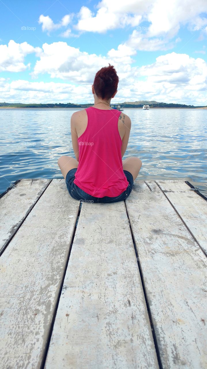 A short haired woman meditating on a deck
