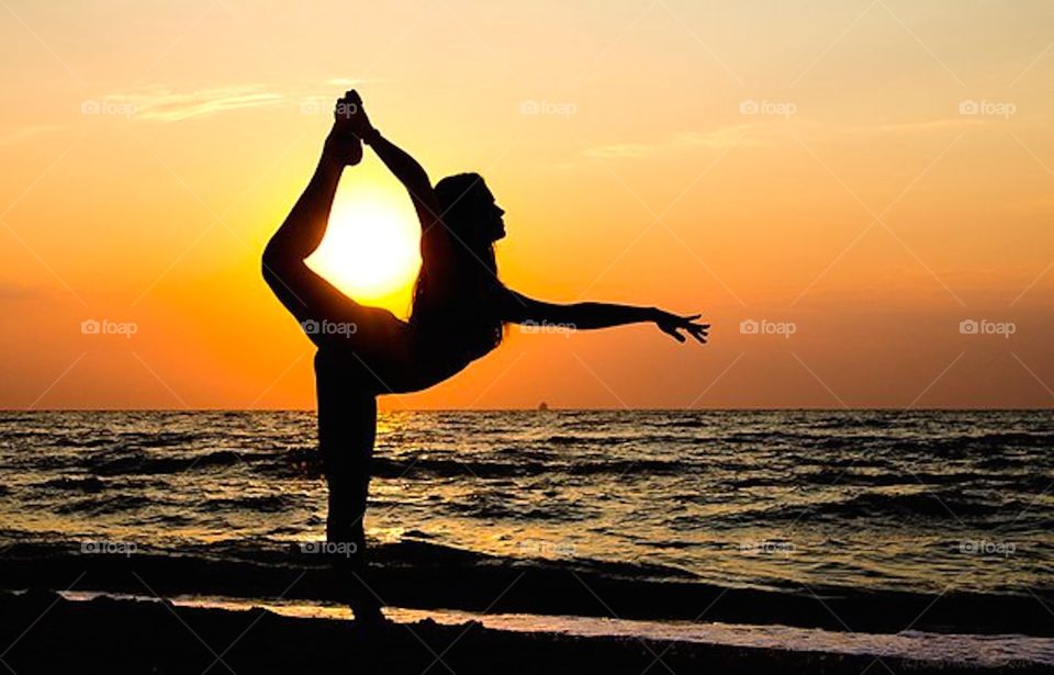 Silhouette of women doing yoga at beach