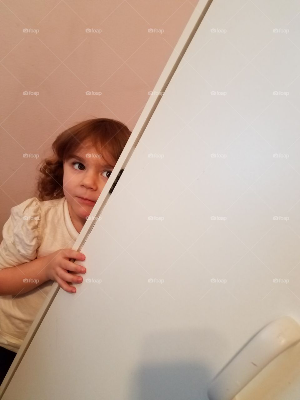 Girl standing behind cupboard