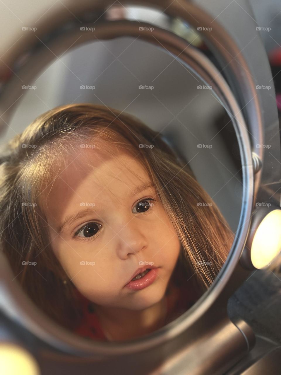 Little girl staring at herself in the mirror 