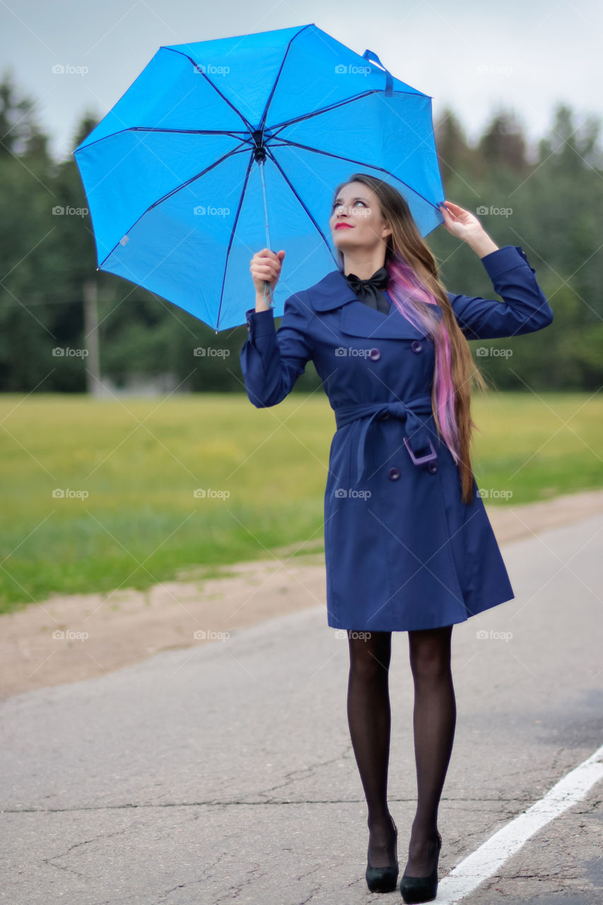 A beautiful girl in a blue costume with the blue umbrella